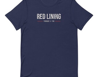 May include: A navy blue short-sleeve t-shirt featuring the white distressed text RED LINING centered on the chest. Below the text is a thin horizontal orange line, the words TORQUE & TIN in white, and another thin orange line.