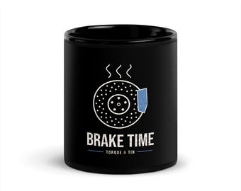 May include: A black ceramic mug featuring a white graphic of a circular brake rotor with a blue brake pad. Above the rotor are three steam lines. Below the graphic, the text reads BRAKE TIME and TORQUE & TIN in white and blue.