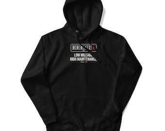 May include: A black hooded sweatshirt featuring a graphic of a car odometer displaying the numbers 000128. Below the odometer, the text reads LOW MILEAGE, HIGH MAINTENANCE. with the smaller text TORQUE & TIN underneath in white and red.