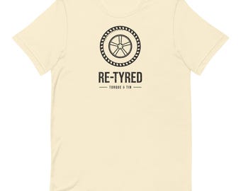 May include: A cream-coloured short-sleeve t-shirt featuring a black graphic of a car tyre and wheel. Below the graphic, the text reads RE-TYRED in a bold, distressed font, followed by the words TORQUE & TIN separated by horizontal lines.