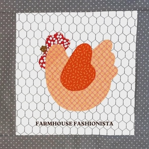 May include: A square fabric quilt block featuring a central applique of a chicken with a peach patterned body, a dark orange wing, and a red floral comb. The background is white with a black chicken wire pattern, bordered by dark gray fabric.