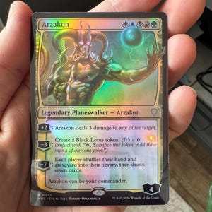 May include: A holographic Magic: The Gathering trading card titled Arzakon, a Legendary Planeswalker. The card features a horned, muscular figure with glowing eyes and a floating orb. It displays mana symbols, loyalty abilities, and the text Arzakon can be your commander, with a loyalty value of 4 at the bottom right.