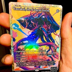 May include: A holographic Magic: The Gathering trading card titled Emrakul, the Exigent Doom. The card features a colorful, abstract illustration of a tentacled creature, a 12/12 power and toughness rating, and text detailing its abilities and game rules.