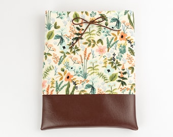 May include: A small, brown leather pouch with a floral print fabric top. The pouch is tied closed with a brown ribbon.