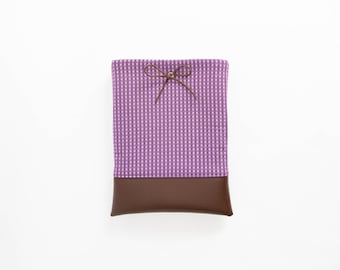 May include: A purple and white gingham fabric pouch with a brown leather bottom and a brown ribbon tied in a bow.