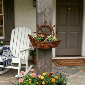 Puede incluir: Una maceta de pared marrón con forma de barco y diseño de timón. La maceta está llena de una variedad de flores pequeñas y coloridas y plantas suculentas verdes, montada en un poste de madera vertical.