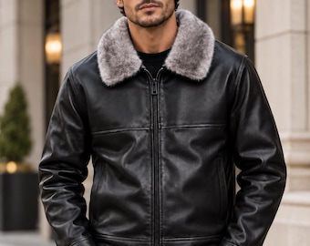 May include: A black leather jacket featuring a full-length front zipper closure, long sleeves with buttoned cuffs, and a plush, grey faux fur collar. The ORIXO LEATHER logo is visible in the upper left corner of the image.