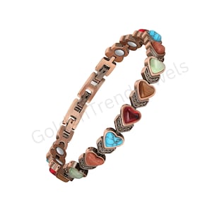 Könnte beinhalten: Ein kupferfarbenes Gliederarmband mit einer Reihe herzförmiger Steine in verschiedenen Farben, darunter Türkis, Rot, Braun und Hellgrün. Das Armband besteht aus Metallgliedern mit integrierten kreisförmigen Magneten auf der Innenseite.
