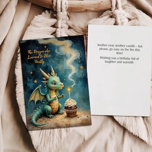 May include: A birthday card featuring a teal dragon blowing out a candle on a cupcake. The card has the text "The Dragon who Learned to Blow Gently" and a message inside. The background is a watercolor style with stars.