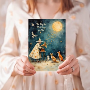 May include: A watercolor print featuring a whimsical scene with a figure in a star-covered coat, a gramophone, and foxes under a full moon. The text on the print reads "The Day the Stars sang for You."