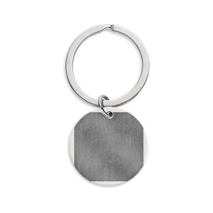 May include: A circular silver-toned metal keychain featuring a flat, brushed-finish disc pendant attached to a standard split ring. The pendant has a smooth, metallic texture with a subtle vertical grain, providing a clean and simple aesthetic.