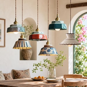 May include: Five hanging pendant lights with ceramic shades in various colours and patterns, including teal geometric, blue striped, solid red, blue floral, and white scalloped designs, all suspended by twisted brown cords with brass hardware.