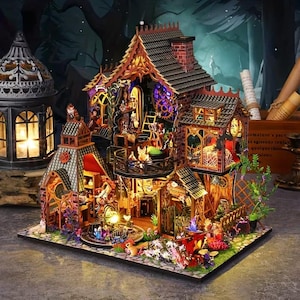 May include: A multi-story miniature wooden house model featuring intricate architectural details, brick-patterned walls, and illuminated interior rooms. The structure includes a balcony, a pitched roof, and various small decorative items like plants and furniture.