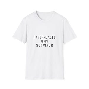 May include: A white short-sleeved t-shirt featuring the black text PAPER-BASED QMS SURVIVOR printed in a clean sans-serif font across the center of the chest. The garment has a classic crew neckline and a standard fit with short sleeves.