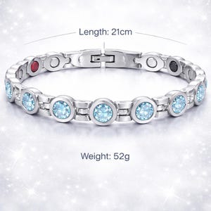 May include: A silver-toned link bracelet featuring round, light blue faceted stones set in each link. The bracelet includes a clasp, a small red stone, and a small black stone. Text indicates a length of 21cm and a weight of 52g for this piece.