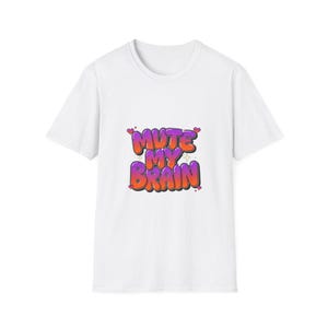 May include: A white short-sleeved t-shirt featuring a central graphic with the text MUTE MY BRAIN in a stylized, bubble-letter graffiti font. The letters transition from orange to purple and are accented with small red hearts and star shapes.