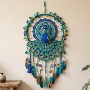 May include: A wall hanging featuring a crocheted peacock with a vibrant blue neck and a fanned tail of green and gold feathers. The peacock is centered within a circular hoop decorated with small crocheted flowers, leaves, and hanging tassels.
