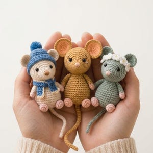 Peut inclure: Trois petites souris en crochet. La souris de gauche est crème avec un bonnet à pompon et une écharpe bleus. La souris centrale est brun doré. La souris de droite est vert sauge avec une couronne de fleurs blanches. Oreilles et pieds roses.