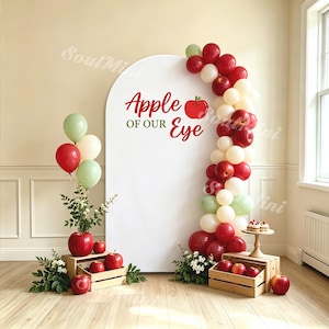 Peut inclure: Une toile de fond arquée blanche avec le texte rouge Apple OF OUR Eye et un graphique de pomme rouge. Une guirlande de ballons rouges, blancs et vert sauge longe le côté droit. Un bouquet de ballons et des caisses en bois remplies de pommes.