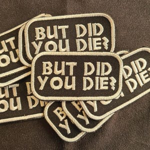 May include: A collection of rectangular embroidered patches featuring a black background with white stitched borders and the text BUT DID YOU DIE? in white capital letters. The patches are stacked in an overlapping arrangement.