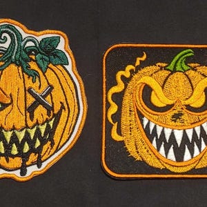 May include: Two embroidered patches featuring pumpkin designs. The left patch is a round orange pumpkin with a green stem, one glowing eye, and a stitched X over the other eye. The right patch is a square black background with a yellow pumpkin.
