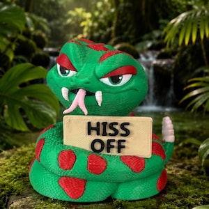 Pode incluir: Uma figura de cascavel impressa em 3D nas cores verde e vermelha, com corpo enrolado, língua bífida rosa e presas brancas. A serpente tem uma expressão zangada e segura uma placa bege com o texto HISS OFF em preto na boca.