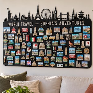 Puede incluir: Un tablero de pared rectangular negro con una silueta de horizonte cortada con láser en la parte superior y el texto "WORLD TRAVEL - SOPHIA'S ADVENTURES". El tablero está cubierto con numerosos imanes de recuerdo coloridos que representan varios monumentos mundiales.