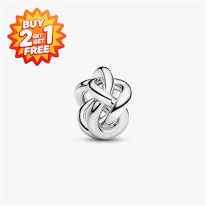 May include: A polished silver-toned charm bead featuring an intricate, multi-loop knot design with a smooth, reflective surface. In the upper left corner, a star-shaped graphic contains the text BUY 2 GET 1 FREE in white and yellow.
