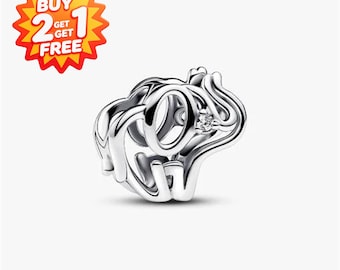 May include: A silver-toned metal charm bead shaped like an elephant with an openwork design. The elephant features a small, clear, round gemstone set into the side of its head. The charm has a hollow center for threading onto a bracelet or chain.