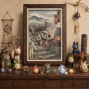 May include: A framed art print featuring a stylized creature eating a rock in a blacksmith shop, surrounded by various small fantasy figurines including a fox, a dragon, and a star. The print includes Japanese text and a warm, earthy color palette.