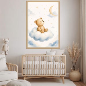 Puede incluir: Una lámina de arte mural enmarcada que muestra un oso de peluche marrón claro sentado sobre una nube azul esponjosa. El fondo es de un color crema suave con una luna creciente amarilla y pequeñas estrellas doradas sobre el oso.