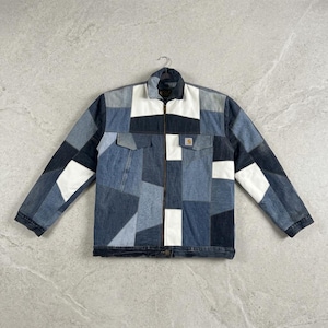 May include: A long-sleeve jacket featuring a patchwork design of denim fabric in various shades of blue, dark navy, and white. The jacket has a full-length front zipper, a collar, and two chest pockets with flaps, one of which displays a Carhartt label.