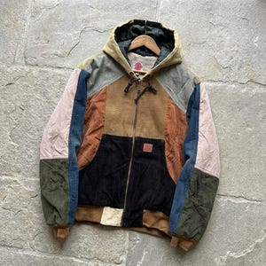 Peut inclure: Une veste à capuche color-block composée de panneaux en velours côtelé et en jean dans des tons beige, marron, noir, vert olive, bleu et rose clair. La veste présente une fermeture éclair intégrale, une capuche à cordon et une étiquette rectangulaire.