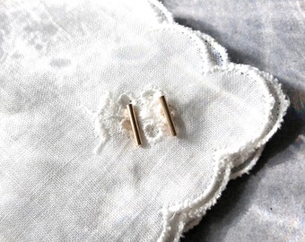 May include: A pair of gold bar stud earrings. The earrings are small and simple, and they are perfect for everyday wear.