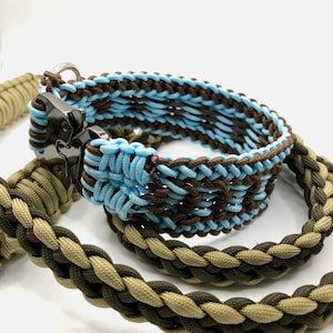 Könnte beinhalten: Ein Haustierhalsband und Leinen-Set aus geflochtenem Paracord. Das Halsband zeigt ein hellblaues und dunkelbraunes Flechtmuster mit einer schwarzen Metallschnalle. Die Leine ist in einem geflochtenen Design aus olivgrüner und beiger Kordel gefertigt.