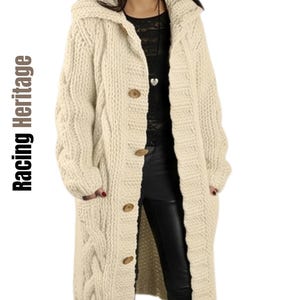 May include: A long, cream-coloured cable knit cardigan featuring a hood, long sleeves, and a front button closure with five brown buttons. The garment has a thick, textured knit pattern and two front pockets. The text Racing Heritage is visible.
