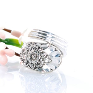 May include: A silver ring made from a vintage spoon with a floral design. The ring is adjustable and can be worn on any finger.