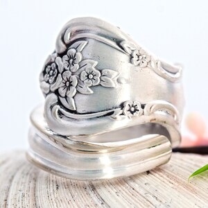 May include: A silver ring made from a vintage silverware spoon with a floral design. The ring is adjustable and can be worn on any finger.
