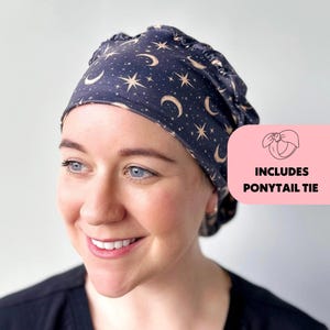 May include: A black scrub cap with a gold moon and star pattern. It includes a ponytail tie.