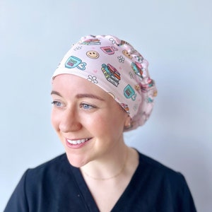 May include: A pink surgical scrub hat with a pattern of books, coffee cups, and flowers. The text "Bookish" is printed on one of the coffee cups.