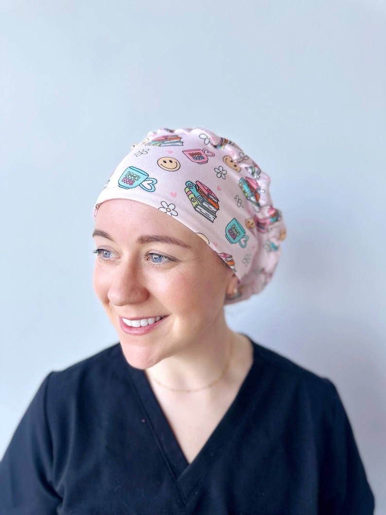 May include: A pink surgical scrub hat with a pattern of books, coffee cups, and flowers. The text "Bookish" is printed on one of the coffee cups.