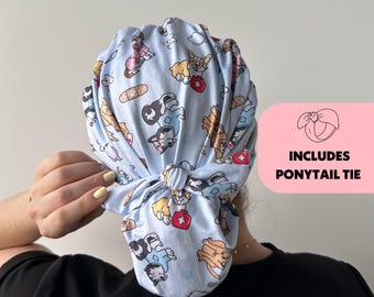 May include: A light blue surgical scrub cap with a repeating pattern of cartoon dogs, bandages, and medical crosses. The cap includes a ponytail tie. The cap is tied in a knot at the back.