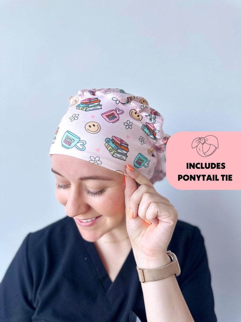 May include: Pink surgical scrub hat with a book and coffee cup print. The hat has a ponytail tie.