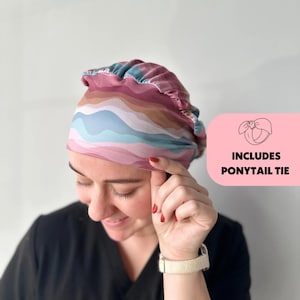 May include: A pink and blue striped surgical scrub hat with a gathered top. The hat includes a ponytail tie. Includes ponytail tie.