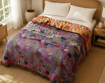 Könnte beinhalten: Eine rechteckige Tagesdecke mit einem lebendigen Blumenmuster in Violett, Orange, Grün und Rot. Die Decke hat eine strukturierte Oberfläche mit Fransen an den Rändern und liegt auf einem Bett mit hellem Holzrahmen und weißen Kopfkissen.