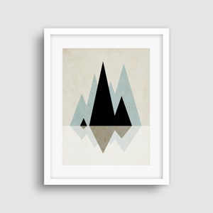 May include: A framed print of a geometric mountain landscape with black and blue triangles on a beige background. The mountains are reflected in the water below.