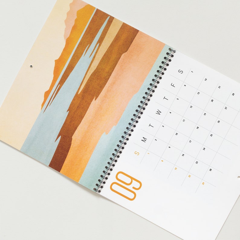 Wall calendar for 2024 with bright colorful abstract landscapes. Coil bound with pre-drilled hole for easy hanging. Calendar grid with space for notes. Opens up to 11x17 inches size. Month of September shown here.