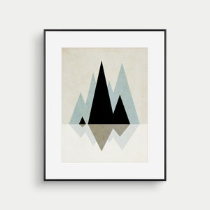May include: A framed print of a minimalist geometric mountain landscape. The mountains are black and blue against a beige background. The mountains are reflected in the water below.