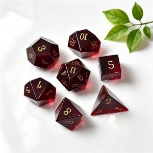 Puede incluir: Un juego de siete dados poliédricos de resina roja translúcida profunda con números de color dorado. La colección incluye un d20, d12, d10, d8, d6, d4 y un dado de porcentaje, todos con bordes afilados y un acabado pulido para juegos de mesa.