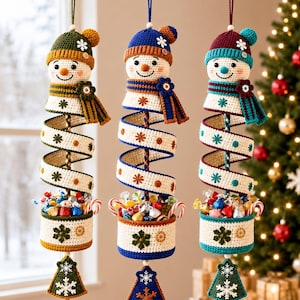 May include: Three hanging crochet snowman ornaments with spiral bodies and candy-filled baskets. Each snowman wears a colourful hat and scarf, featuring snowflake motifs and small buttons. The base of each ornament is a triangular tree shape.